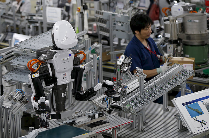 A humanoid robot works side by side with employees in the assembly line at a factory of Glory Ltd., a manufacturer of automatic change dispensers, in Kazo, north of Tokyo, Japan (Reuters Photo)