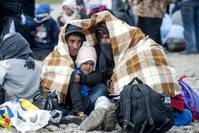 Migrants and refugees huddle together as they wait to enter a registration camp after crossing the Greece-Macedonia border near Gevgelija.