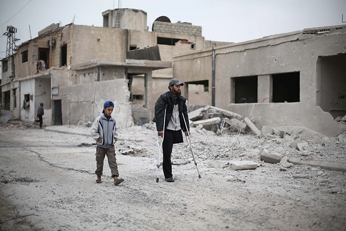 A Syrian man walks with his son amid damaged buildings in the Marj al-Sultan neighbourhood east of the capital Damascus on October 25, 2015 (AFP Photo)