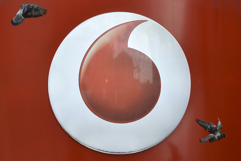 Pigeons fly past Vodafone branding outside a retail store in London November 12, 2013 (Reuters Photo)