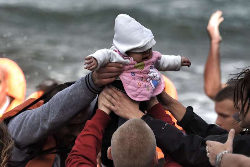 A baby is carried by migrants as they arrive on the Greek island of Lesbos after crossing the Aegean Sea from Turkey.