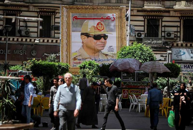 Egyptians walk past a poster bearing a portrait of retired army chief and current President AbdelFattah el-Sissi.
