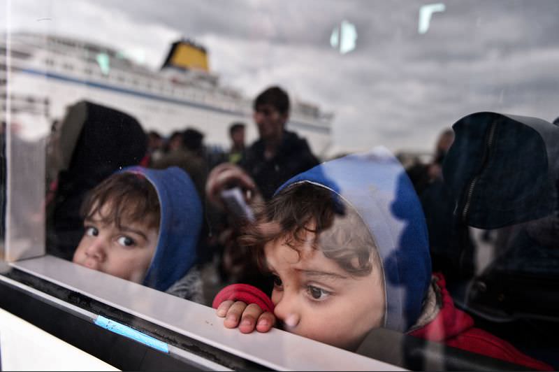 Refugee children peek out from a bus taking them to the city's center, after disembarking from a government chartered ferry at the port of Piraeus on October 30, 2015. (AFP Photo)
