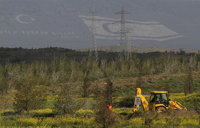 In this Feb. 9, 2010 file photo, the flag of the Turkish Republic of Northern Cyprus is seen on a mountain in the background as an expert from the Committee on Missing Persons searches for human remains at a field near Nicosia, Cyprus (AP Photo)