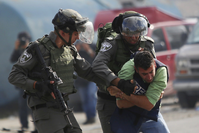 Israeli police wrestle a Palestinian cameraman during clashes outside Ramallah, West Bank.
