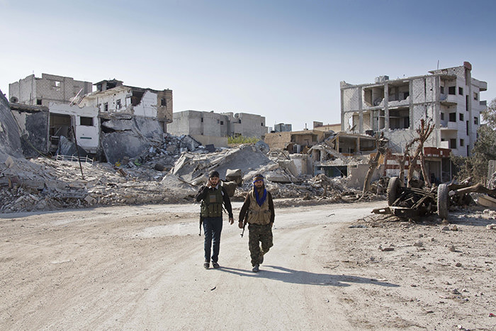 YPG soldiers walk near the town entrance circle heading to their strongholds in Kobani, Syria (AP Photo)
