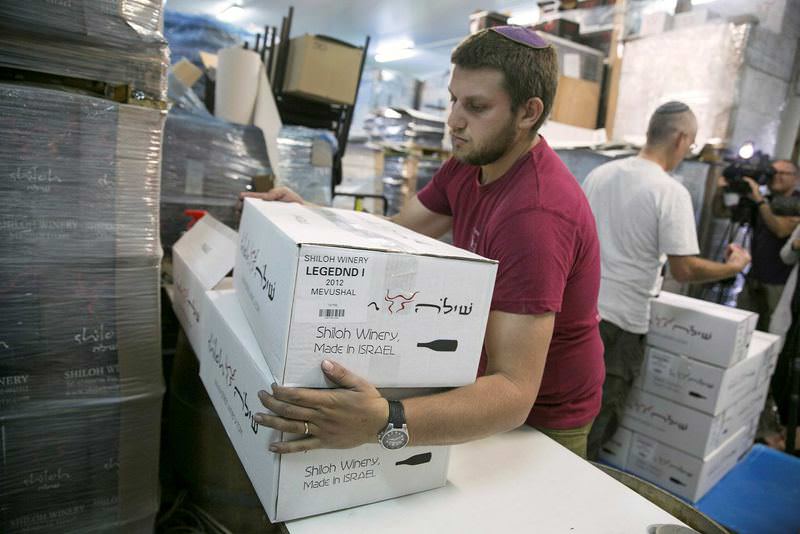A worker carries boxes containing wine bottles and will have to label them as produced in occupied territories to export the EU countries.