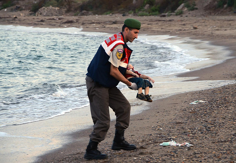 The image Blasio shows durnig his speech: A Turkish gendarmerie officer carries three-year-old Aylan Kurdi's body (DHA Photo)