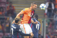 Galatasaray's Podolski (C), fights for the ball with Antoine Griezmann (L) and Jackson Martinez of Atletico Madrid during the Champions League.