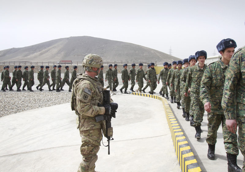 A U.S. soldier, left, watches members of the Afghan Public Protection Force arrive at the transition ceremony of private security forces on March 2012. (AP Photo)