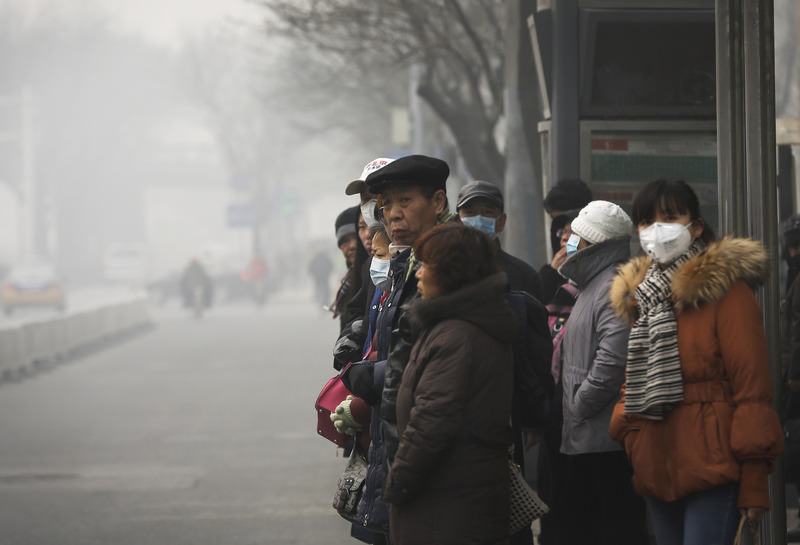 Commuters, some wearing masks to protect themselves from pollutants, wait at a bus stand on a heavily polluted day in Beijing, Monday, Nov. 30, 2015. (AP Photo)
