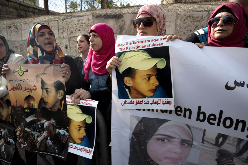 Protesters hold posters of Palestinian teenager Mohammed Abu Khdeir, who was killed last year, outside the district court in Jerusalem on November 30, 2015. (AFP Photo)