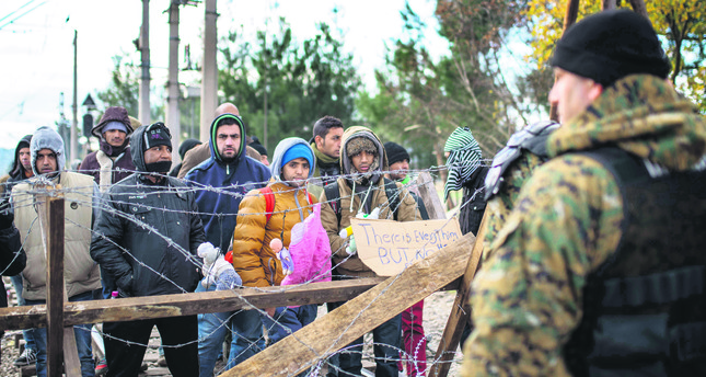 Migrants demonstrate in front of Macedonian police as they wait to cross the Greek-Macedonian border near Gevgelija.