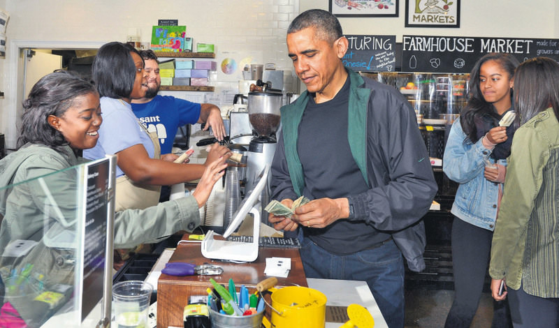 U.S. President Barack Obama (C) pays for purchases at Pleasant Pops, as daughters Malia and Sasha (R) enjoy a popsicle, in Washington D.C. in ,Small Business Saturday.,