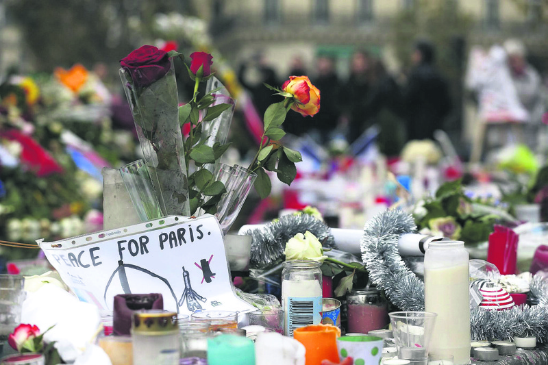 People leave French national flags, candles and flowers at a makeshift memorial in Paris for the 130 people who were killed in a terror attack, claimed by DAESH.