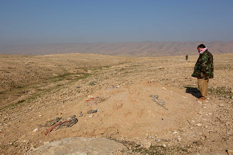 A member of the peshmerga forces inspects bones, suspected to belong to members of Iraq's Yazidi community, are seen at mass grave in Sinjar, Nov 30, 2015 (Reuters photo)