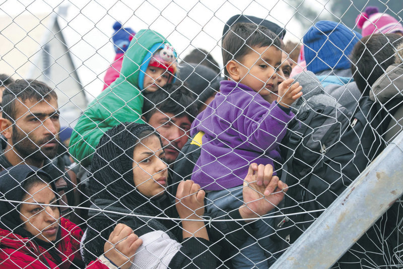 Stranded migrants awaiting entry into Macedonia on the Greek side of the border were photographed through a fence from the Macedonian side of the border 