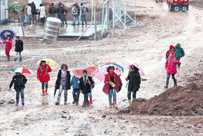 Refugee children hold umbrellas as they go to school on a rainy day in Arbil November 9, 2015.