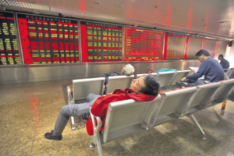 A Chinese investor naps while monitoring stock prices at a brokerage house in Beijing, Friday, Dec. 4, 2015. 