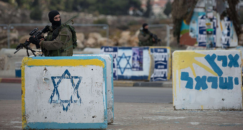 An Israeli soldier from the elite infantry unit stands guard at the Gush Etzion junction in the Israeli occupied on the main road between Jerusalem and Hebron on December 2, 2015 (AFP Photo)
