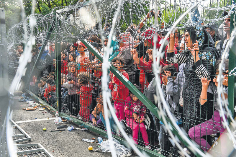 Refugees stand behind a fence at the Hungarian border with Serbia near the town of Horgos on Sept. 16.