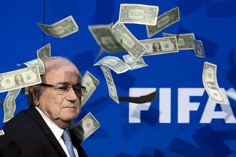This file photo taken on July 20, 2015 shows FIFA president Sepp Blatter looking on with fake dollars note flying around him thrown by a protester (AFP photo)