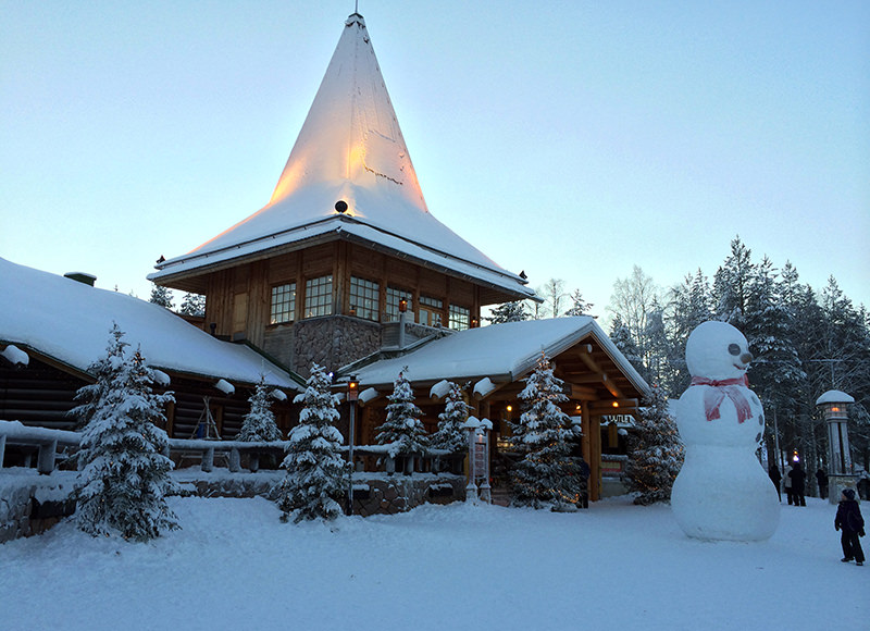 A child looks at a large snowman in Santa Claus Village, around 8 kms, 5 miles north of Rovaniemi in Finland on Tuesday Dec. 15, 2015. (AP Photo)