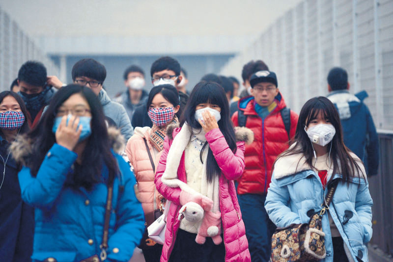 Pedestrians wearing face masks walk along an elevated walkway amid heavy air pollution in Beijing. (AFP Photo)