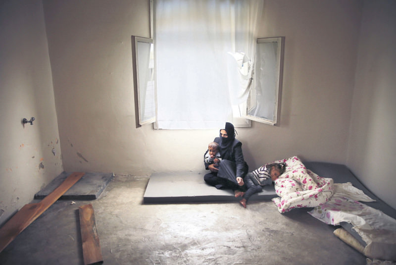 Syrian refugee Hind Salem, who fled the Russian airstrikes with her family from the Syrian town of Palmyra, sitting on the ground with her kids in their unfurnished home in Reyhanlu0131, southern Turkey.