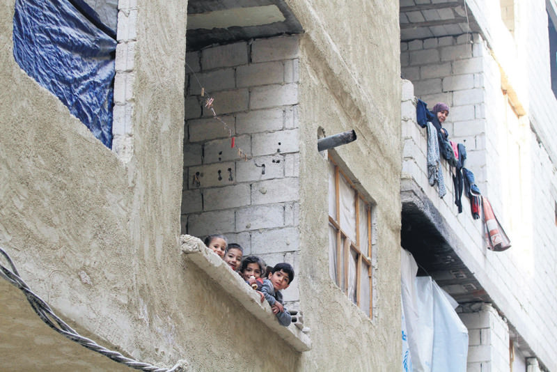 Syrian children look out from an incomplete building where they live with their families in the Daf al-Sakhr neighborhood of Jaramana on the outskirts of Syrian capital Damascus
