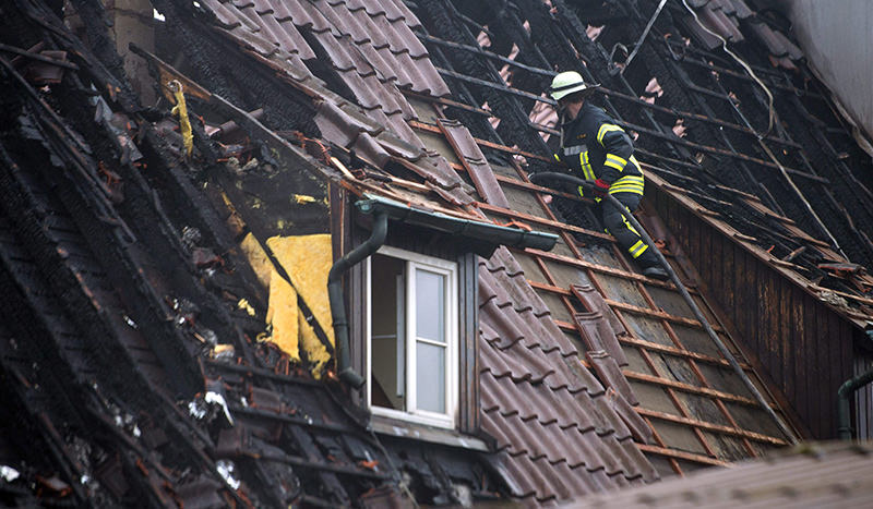 A firefighter stands on the rooftop of a refugee shelter for children and adolescents after a fire broke out, in Ruppertshofen, Germany (EPA Photo)