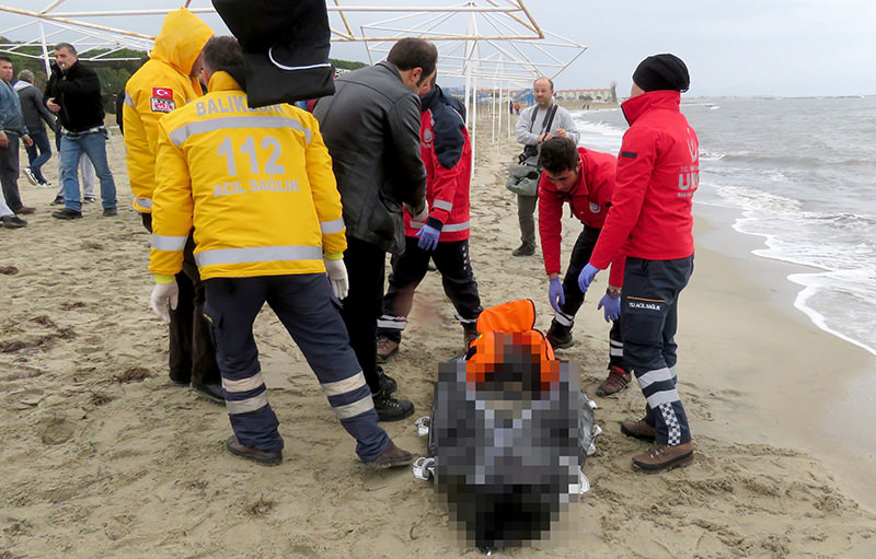 Turkish coast guards and medical team examine the dead migrants. (AA Photo)