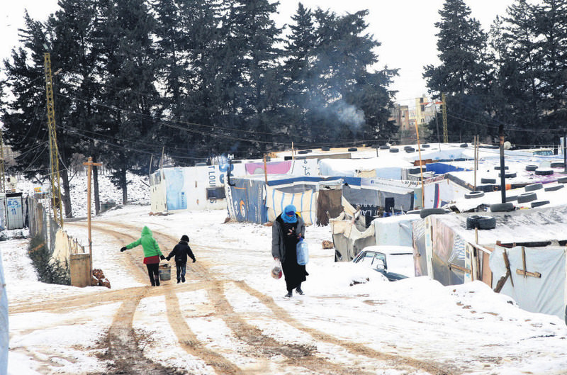Syrian refugees walking in the snow outside their tents at the Barelias refugee camp in Beqaa Valley, eastern Lebanon.