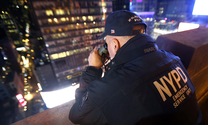 A New York police officer uses binoculars while keeping watch from a rooftop along Times Square (AP Photo)