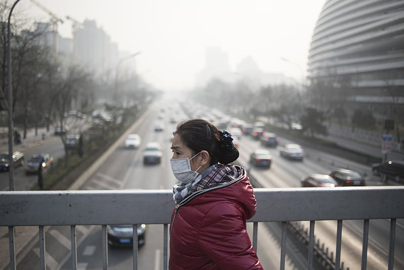 A woman wears a mask as she walks in a street on the 3rd day of a ,red alert, for pollution in Beijing on Dec 21, 2015.  (REUTERS Photo)