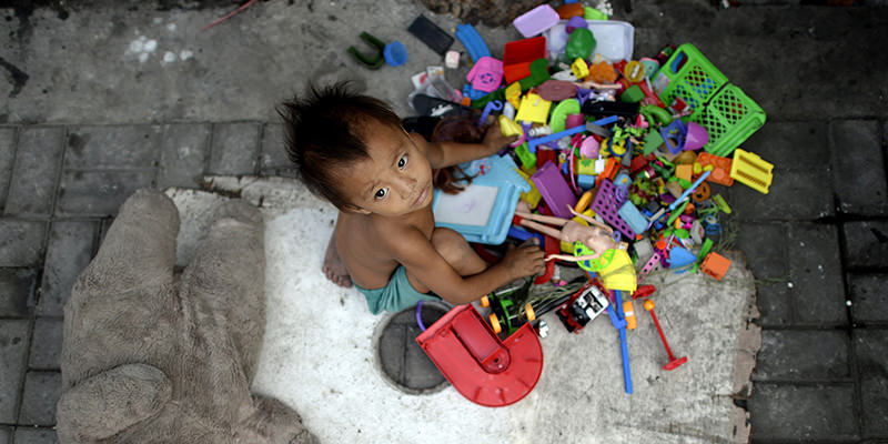 A homeless boy plays with different toys collected by his parents that picks used plastic soda bottles to sell at junk shops in Manila on January 13, 2016 (AFP Photo)