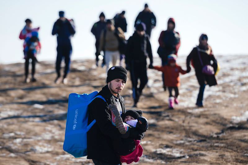 A man carries his child as they walk with other migrants and refugees after crossing the Macedonian border into Serbia near the village of Miratovac on Tuesday.
