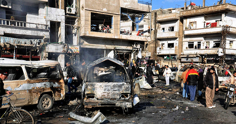 A handout picture made available by Syrian Arab news agency SANA shows Syrian policemen and citizens inspect the site of two terrorist bomb attacks at a security checkpoint in the residential neighborhood of Zahra (EPA Photo)