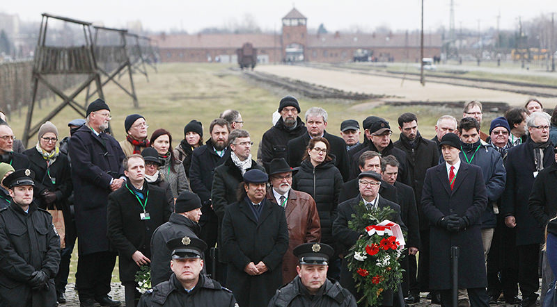 Visitors stand next to a ramp at the former Nazi-German concentration camp KL Auschwitz II-Birkenau during a ceremony in Oswiecim, Poland (AP Photo)