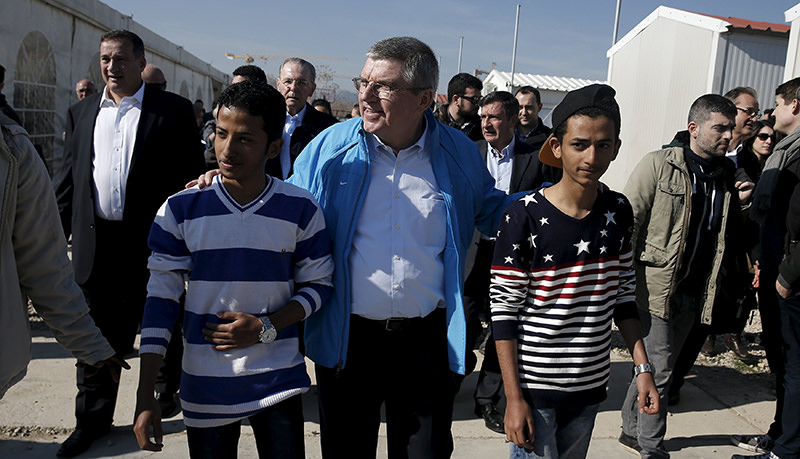 International Olympic Committee President (IOC) Thomas Bach (C) walks along with migrants during a guided media tour at the Eleonas refugee camp in Athens, Greece, January 28, 2016