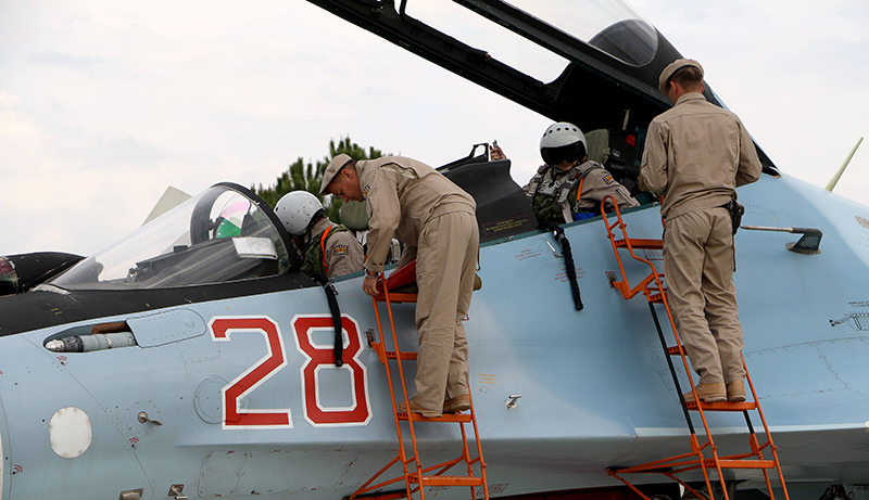 Russian servicemen assist air force pilots in a Russian Sukhoi Su-30SM fighter jet before departure on a mission at the Russian Hmeimin military base in Latakia province (AFP Photo)