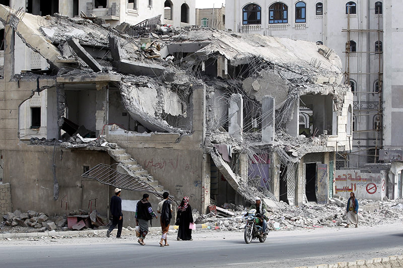Yemenis walk past a building destroyed by a Saudi-led airstrike targeting a neighborhood, in Sana'a, Yemen, 01 February 2016 (EPA Photo)