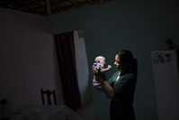 Juliana da Silva, is illuminated by a ray of sunlight as she poses for a photo holding her daughter Maria, who was born with microcephaly due to the Zika virus. (AP Photo)