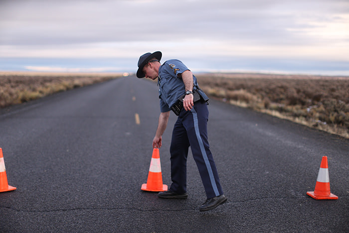 An officer with the Oregon State Police moves a cone to establish a roadblock along one of the routes to the Malheur National Wildlife Refuge in Harney County, Ore (AP Photo)