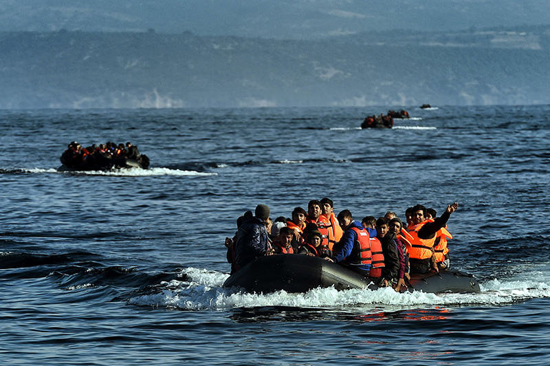 Refugees aboard dinghies reach the Greek island of Lesbos after crossing the Aegean sea from Turkey on October 4, 2015 (AFP)