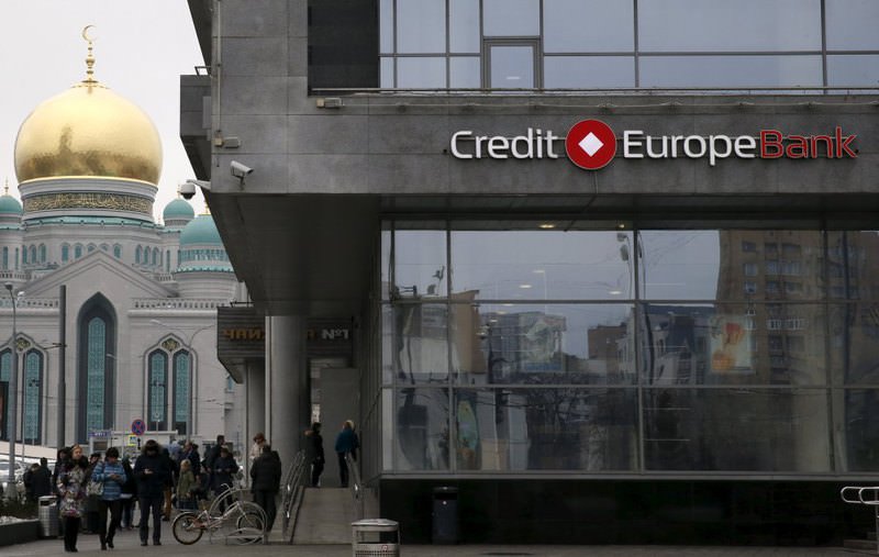 People walk near a branch of the Credit Europe Bank, with a mosque seen in the background, in Moscow, Russia.