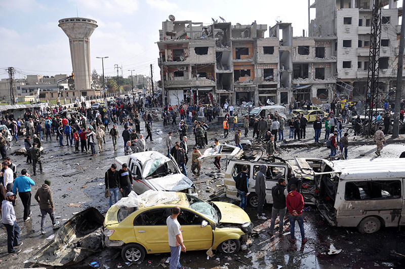 Syrians gather at the site of a double car bomb attack in the Al-Zahraa neighbourhood of the central Syrian city of Homs on February 21, 2016 (AFP)