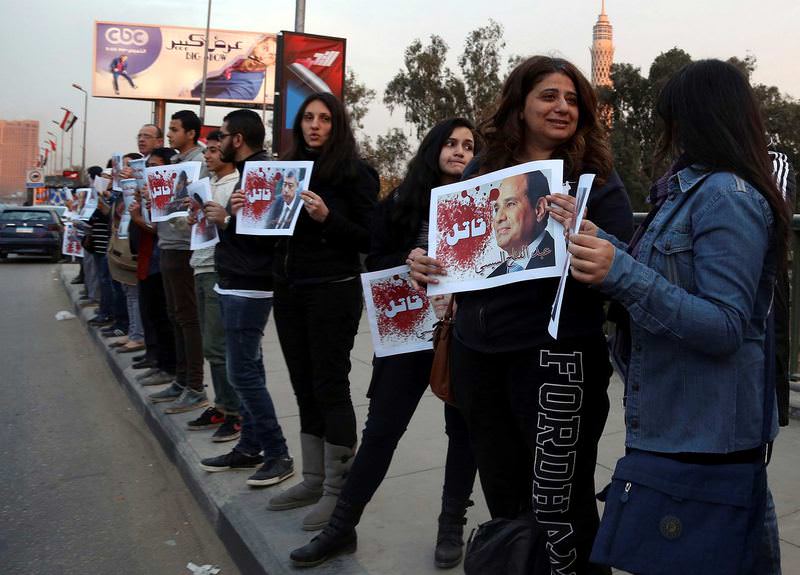 Protesters hold posters of Egyptian President Abdel Fattah el-Sissi (R) and Interior Minister Mohamed Ibrahim with the word ,Killer, on it during a silent protest over a bridge in Cairo.