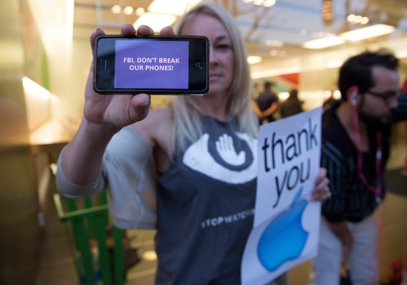 A demonstrator shows a cellphone with a banner in front of an Apple Store in San Francisco. 