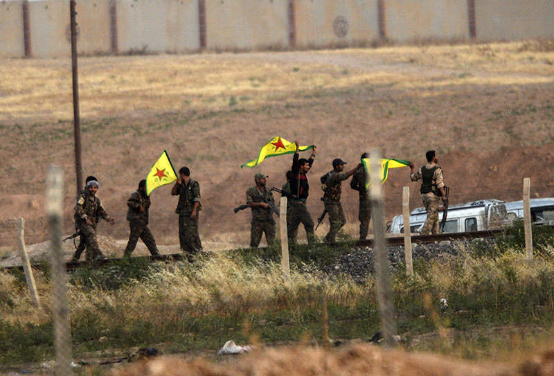 YPG forces hold their movement's flag near the Aku00e7akale crossing gate between Turkey and Syria at Aku00e7akale in u015eanlu0131urfa province on June 15, 2015. (AFP)